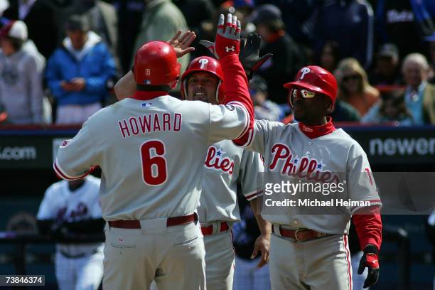 Ryan Howard of the Philadelphia Phillies is greeted at home by Shane Victorino and Jimmy Rollins after his three-run homer in the sixth inning...