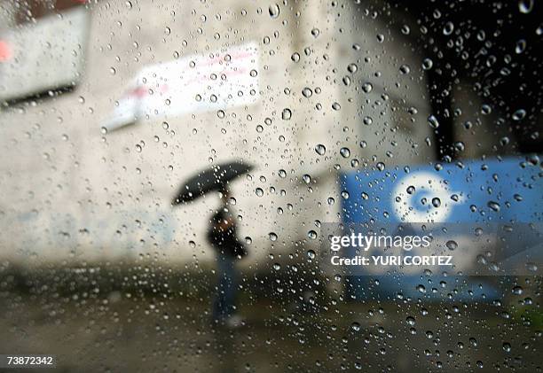 Un costarricense camina con su paraguas por una calle de San Jose el 12 de abril de 2007. Segun el Instituto Metereologico Nacional, el fenomeno de...