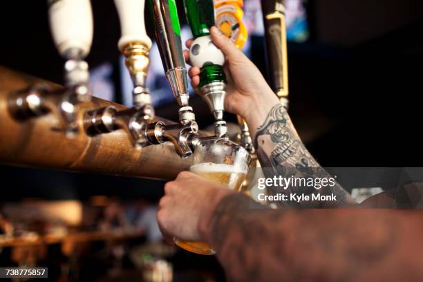 tattoos on arm of bartender pouring beer - bier zapfhahn stock-fotos und bilder