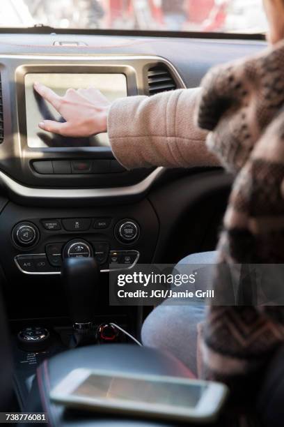 caucasian woman sitting in car pressing touch screen - auto radio stockfoto's en -beelden