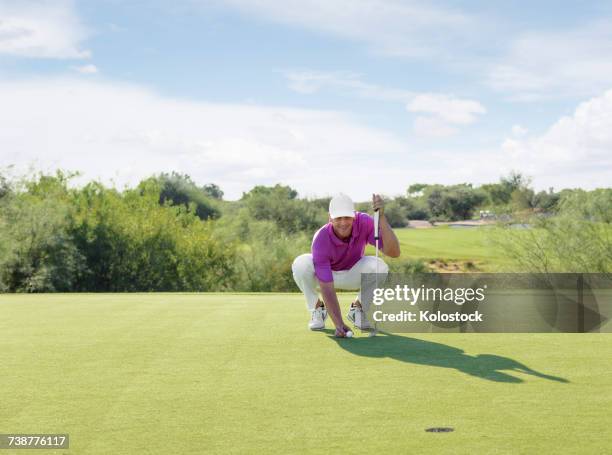 hispanic golfer crouching on golf course - golfer putting stock pictures, royalty-free photos & images