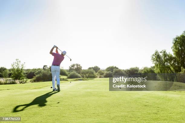 hispanic golfer teeing off on golf course - tee off fotografías e imágenes de stock