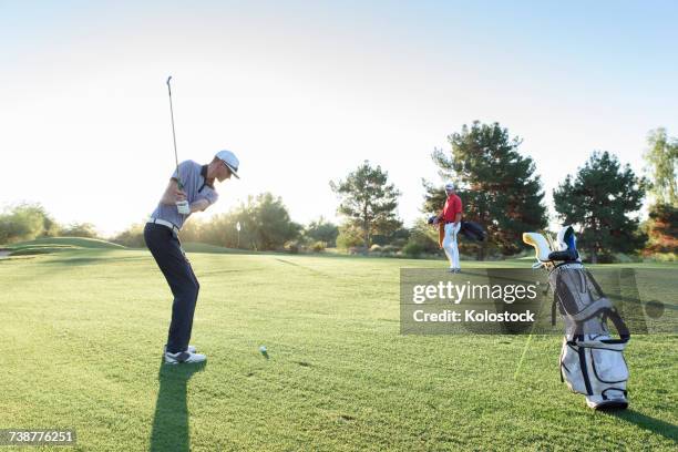 friend watching man hitting ball on golf course - tiro curto imagens e fotografias de stock