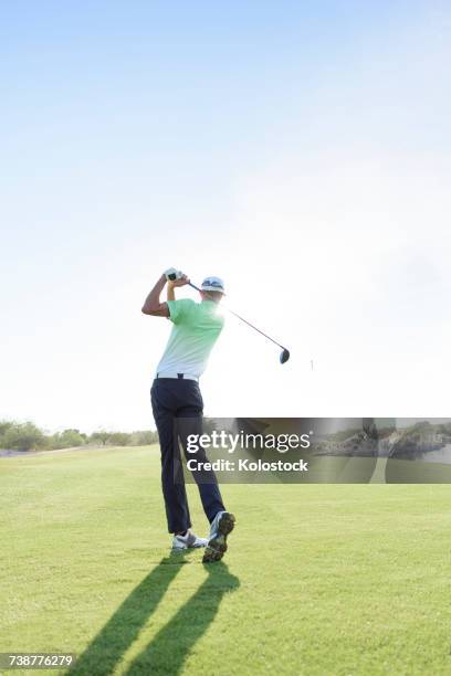 caucasian man teeing off on golf course - golf swing from behind stock pictures, royalty-free photos & images