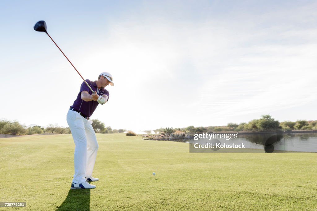 Hispanic man teeing off on golf course