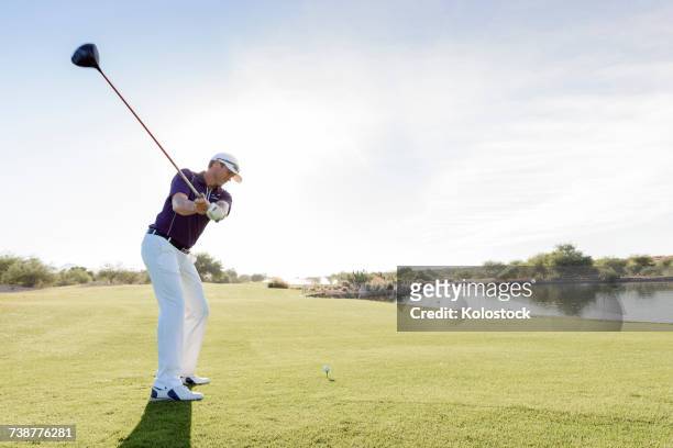 hispanic man teeing off on golf course - play off stock pictures, royalty-free photos & images