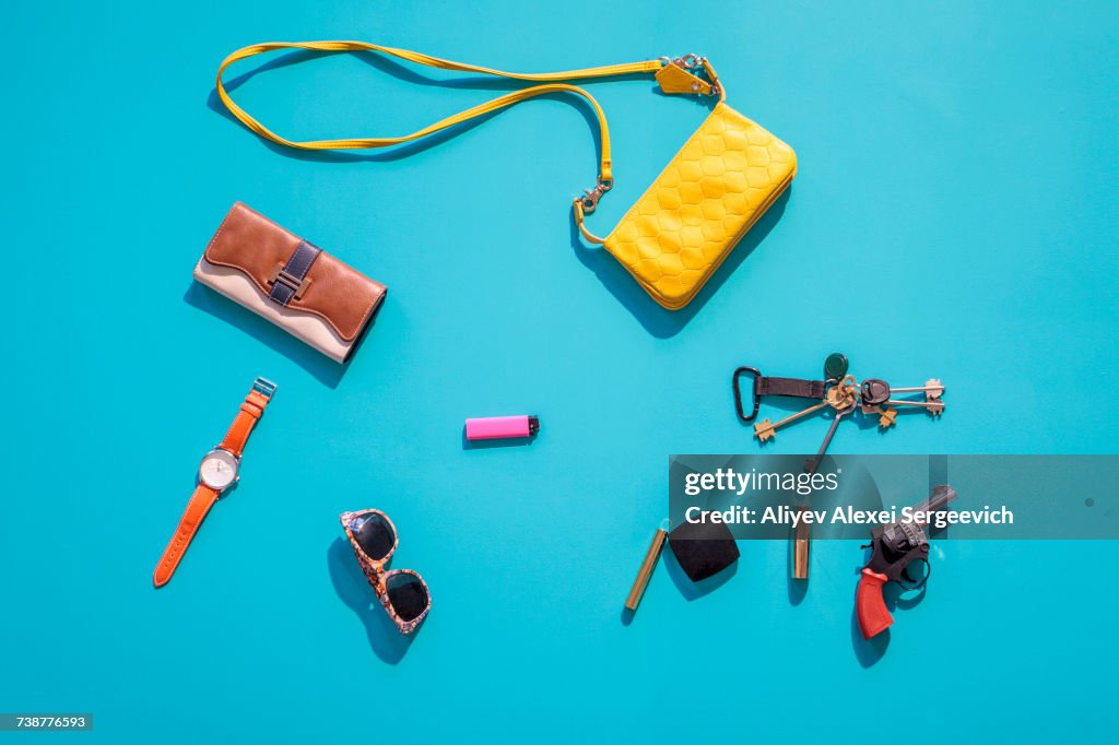 Purse, wallet, gun and accessories on blue background
