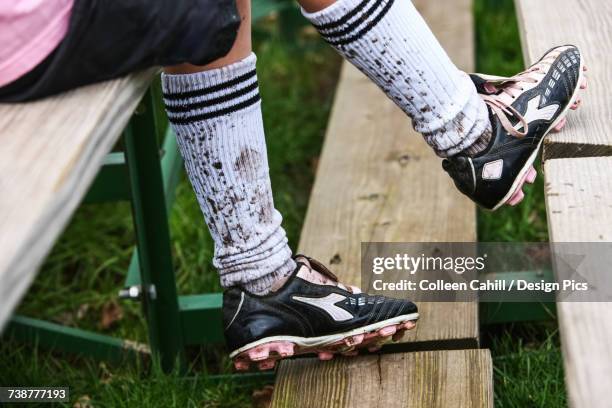 a soccer player sitting on wooden stands wearing cleats and mud splashed socks - chaussettes sales photos et images de collection