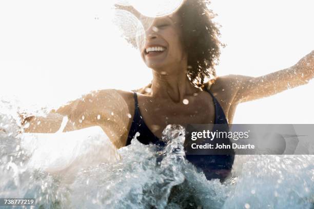 ocean waves splashing on mixed race woman - african woman swimming stock pictures, royalty-free photos & images