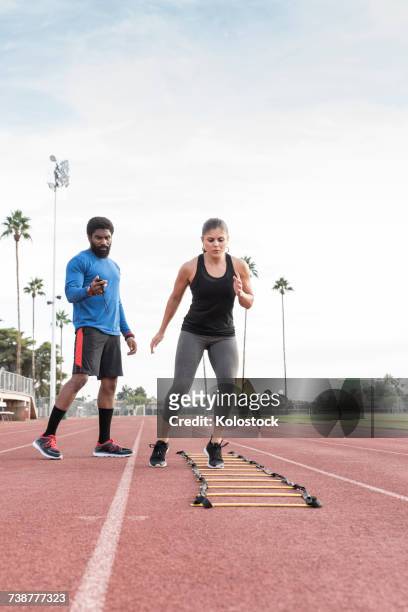 trainer watching woman running ladder - agility ladder ストックフォトと画像