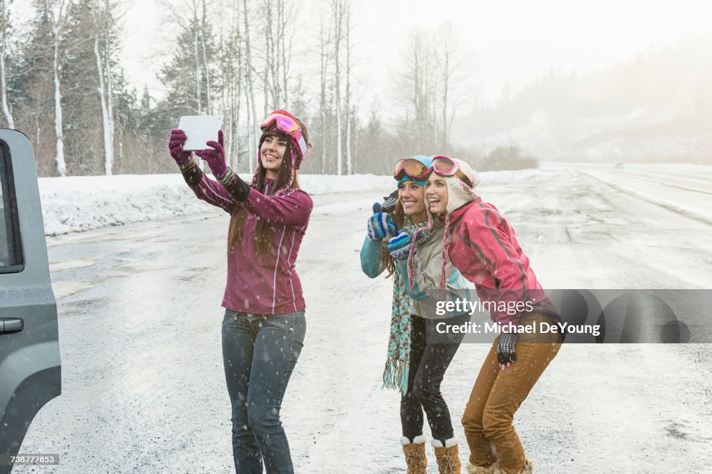 Women posing for cell phone selfie in winter using digital tablet