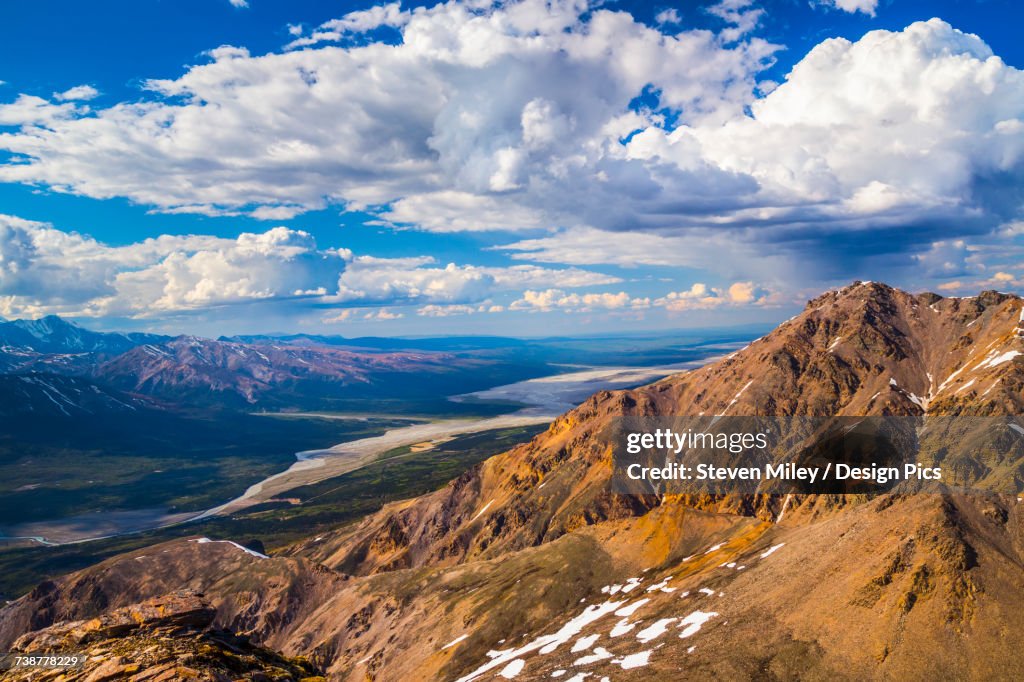 Afternoon storm clouds develop over the mountain ridges of the Alaska Range and the Delta River