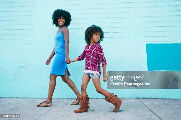 smiling mother and daughter walking on sidewalk - walking side by side stock-fotos und bilder