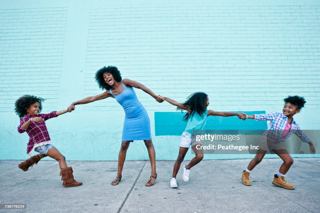 Girls pulling arms of woman in opposite directions