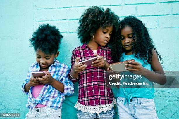 girls leaning on wall texting on cell phones - facebook profile stock pictures, royalty-free photos & images