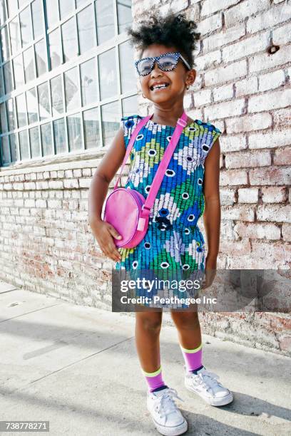 smiling black girl standing on sidewalk wearing dress and purse - schwarze handtasche stock-fotos und bilder