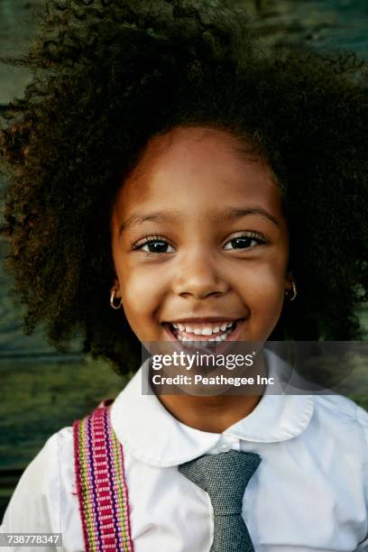 portrait of smiling mixed race girl near wooden wall - school tie stock-fotos und bilder