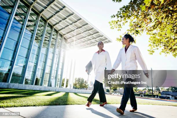 doctors walking and talking outdoors at hospital - medical building exterior stock pictures, royalty-free photos & images