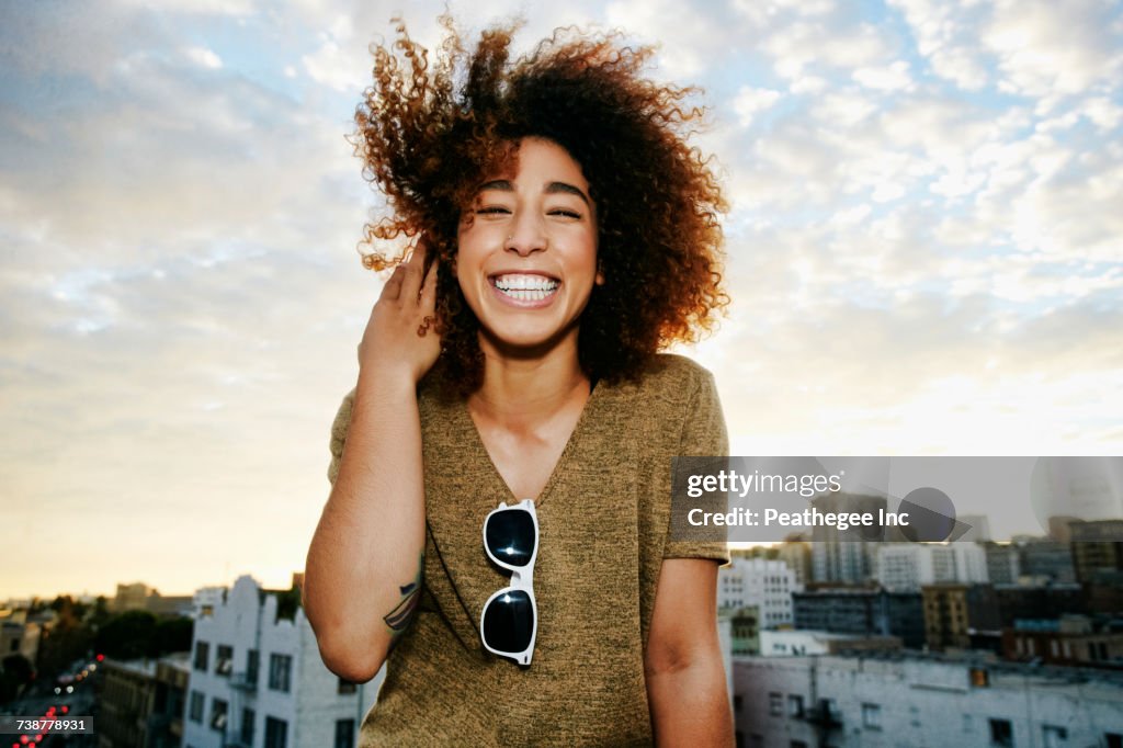 Portrait of smiling Hispanic woman on urban rooftop at sunset