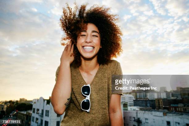 Portrait of smiling Hispanic woman on urban rooftop at sunset
