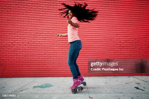 black woman dancing on roller skates on sidewalk - skate sports footwear stock-fotos und bilder