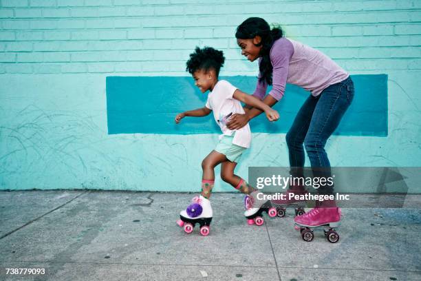 mother holding waist of daughter wearing roller skates - man made space stock pictures, royalty-free photos & images