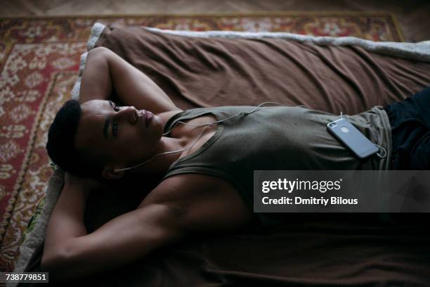 black man laying on bed listening to music on cell phone - hands behind head stock pictures, royalty-free photos & images
