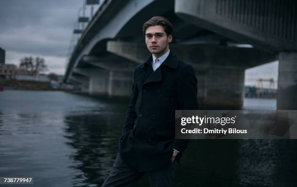portrait of serious caucasian man standing under bridge - ピーコート ストックフォトと画像