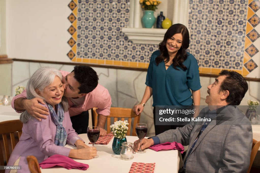 Younger couple greeting older couple in restaurant