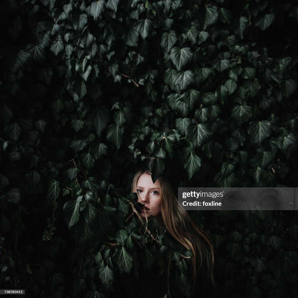 Woman hiding in an ivy bush