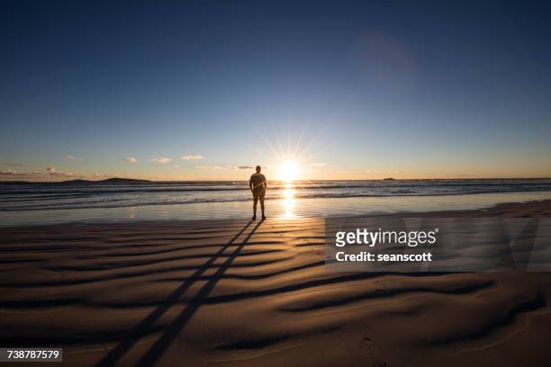 man standing on beech looking at the sunset, western australia, australia - person standing far stockfoto's en -beelden