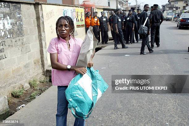 Female INEC official waites for police escorts standing behind to lead her to a polling station at Ilupeju district in Lagos Saturday 14 April, 2007....