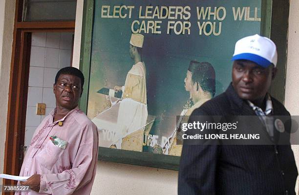 Port Harcourt, NIGERIA: Men walk past a poster at the Electoral Commission , 14 April 2007, in Port Harcourt. Nigerians voted 14 April in elections...