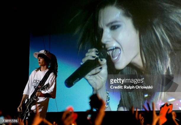 Guitarist Tom Kaulitz of German pop group "Tokio Hotel" performs on stage in front of a huge video screen, showing his brother Bill, during a concert...