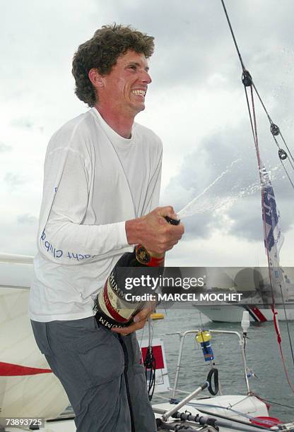 Marie-Galante, FRANCE : French skipper Thomas Rouxel on his "Defi Mousquetaire" monohull, sprays champagne after his arrival at the second place of...