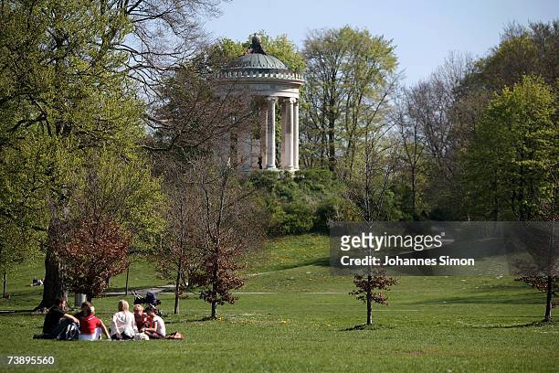 Young people enjoy the warm weather in front of the Monopteros in the world famous Englischer Garten on April 16 in Munich, Germany. The...