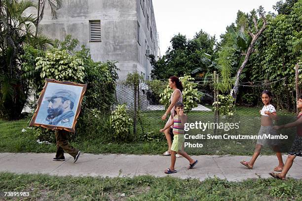 Painting of Fidel Castro is held while people walk towards a political rally, supporting Fidel and the Revolution, 4 days after Fidel Castro had...