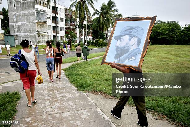 Painting of Fidel Castro is held while people walk towards a political rally, supporting Fidel and the Revolution, 4 days after Fidel Castro had...