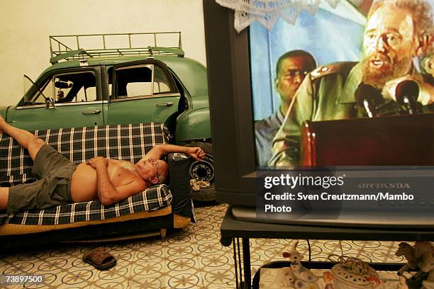 Cuban man listens to a re-transmission of a Fidel Castro speech , in his living room, where he parks his vintage car Chevrolet July 29, 2006 in...
