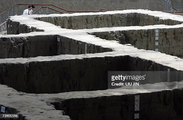 Two visitors view an original excavation site at the newly opened Jinsha Museum in Chengdu, southwest China's Sichuan province 16 April 2007. With an...