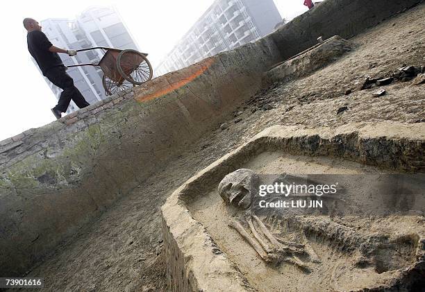 Worker pushes a cart pass the grave chamber at the excavation site near the Jinsha Museum in Chengdu, southwest China's Sichuan province 07 February...