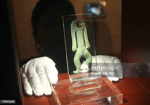 Museum staff places the bronze figure for display prior to the opening of the Jinsha Museum in Chengdu, southwest China's Sichuan province 15 April...