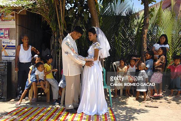 Filipino newlyweds Richard Laureo, and Adema Rapsing with cash gifts pinned on their wedding clothes by relatives, dance in the street outside the...