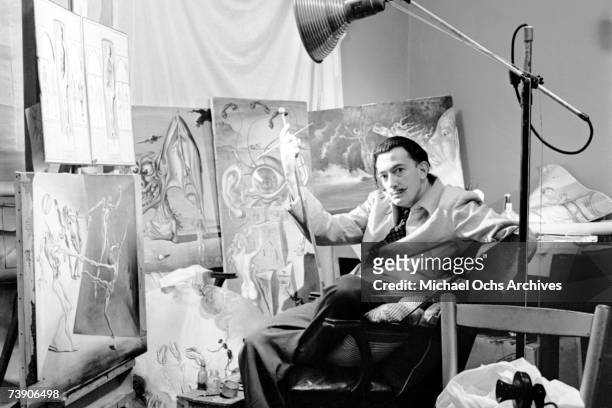 Surrealist artist Salvador Dali poses with his oil paintings at his studio on the 8th floor of the Zeigfeld Theatre in 1943 in New York City, New...