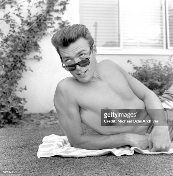 Actor Clint Eastwood lies on a towel and looks over his sunglasses at home on June 1, 1956 in Los Angeles, California.