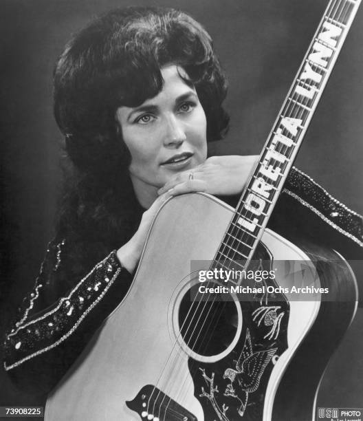 Loretta Lynn poses for a portrait holding a guitar that has her name spelled down the fretboard in circa 1961 in Nashville, Tennessee.