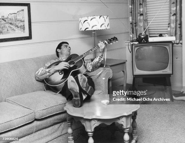 Country singer/songwriter Johnny Cash reclines on a couch while playing acoustic guitar in 1960 in Nashville, Tennessee.