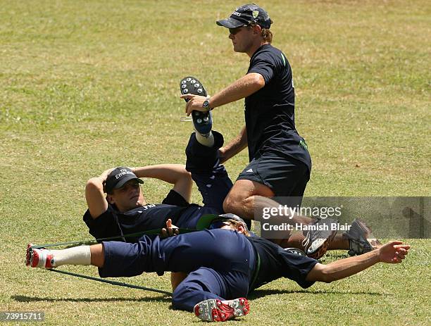 Nathan Bracken of Australia is assisted in his warm up by fitness coach Justin Cordy whilst team mate Shane Watson also stretches during training at...