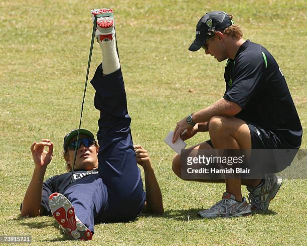 Shane Watson of Australia stretches with fitness coach Justin Cordy looking on during training at La Sagesse Cricket Ground on April 18 in St...