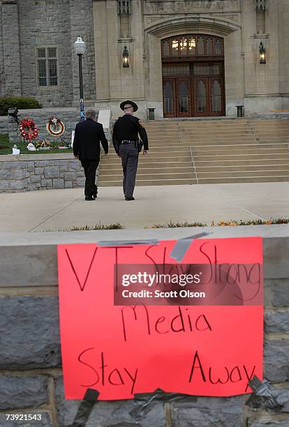 Virginia State Trooper escorts Virginia Tech University President Charles Steger to Burruss Hall, past a memorial erected to honor students who died...
